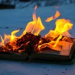 burning book in the snow. pages with the text in the open book burn with a bright flame.